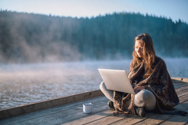 Beautiful woman using laptop and drinking coffee in nature.